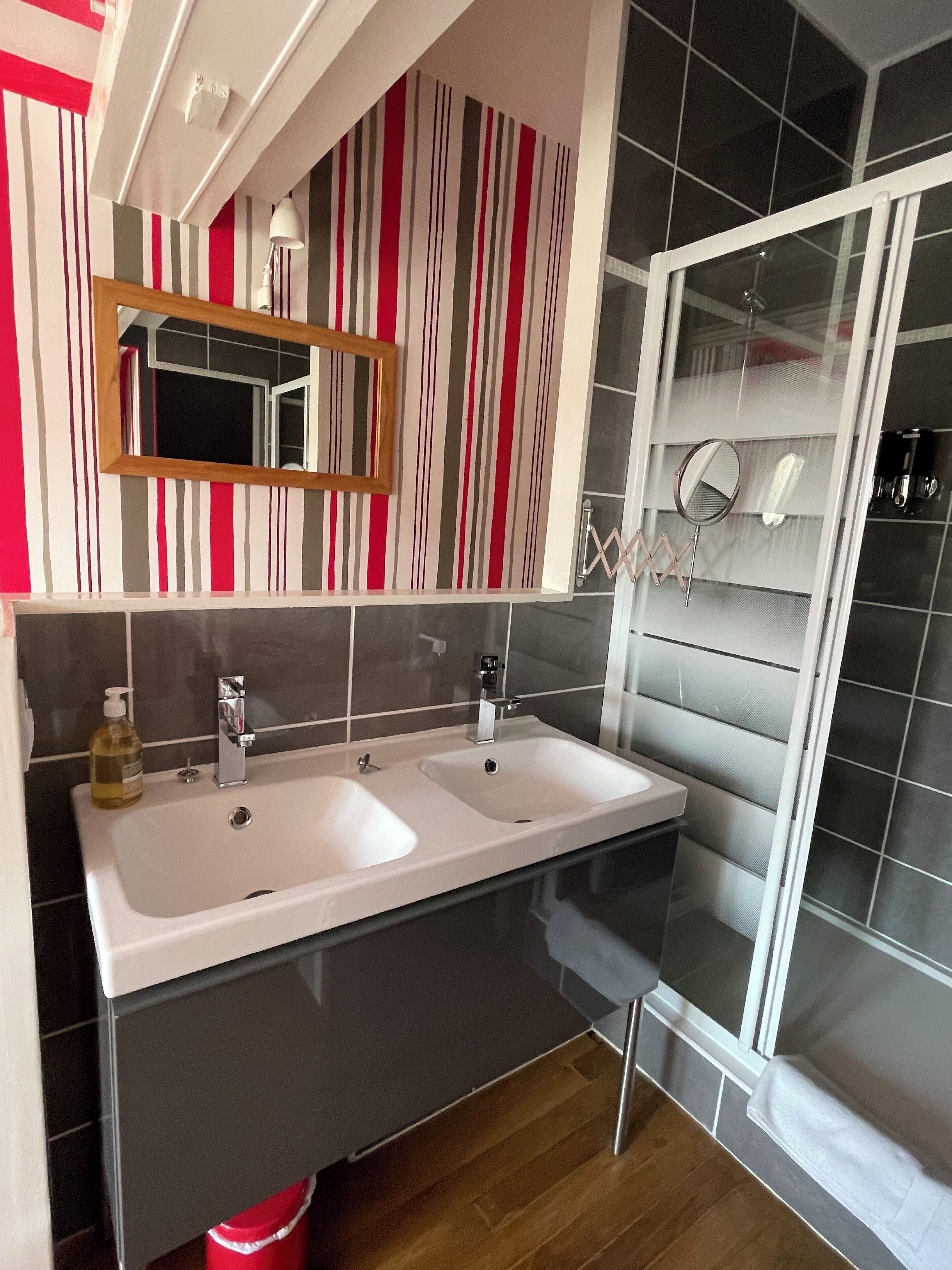 Ein modernes Badezimmer mit zwei Waschbecken, einem Spiegel und einer Duschkabine.
