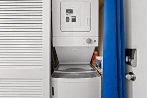 Vista frontal de uma máquina de lavar e secar compacta, com painel de controle e um pequeno compartimento de armazenamento.