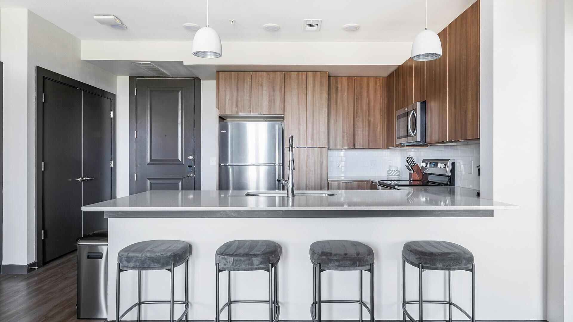 Une cuisine moderne dotée d’un îlot central, d’appareils électroménagers en acier inoxydable et de meubles de rangement en bois.