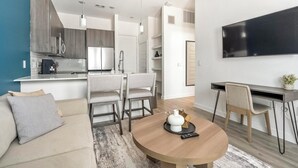 Eine moderne Wohnung mit Wohnzimmer, Essbereich, Küche und einem an der Wand befestigten Fernseher.