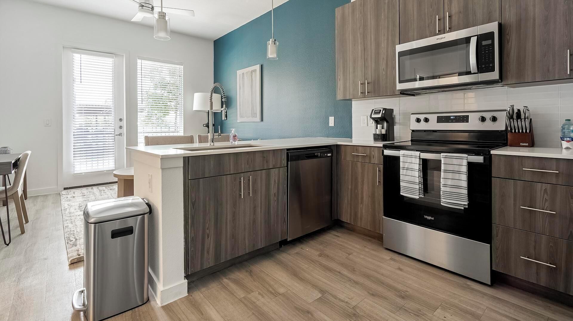 A modern kitchen with a dishwasher, stove, microwave, and a coffee maker.