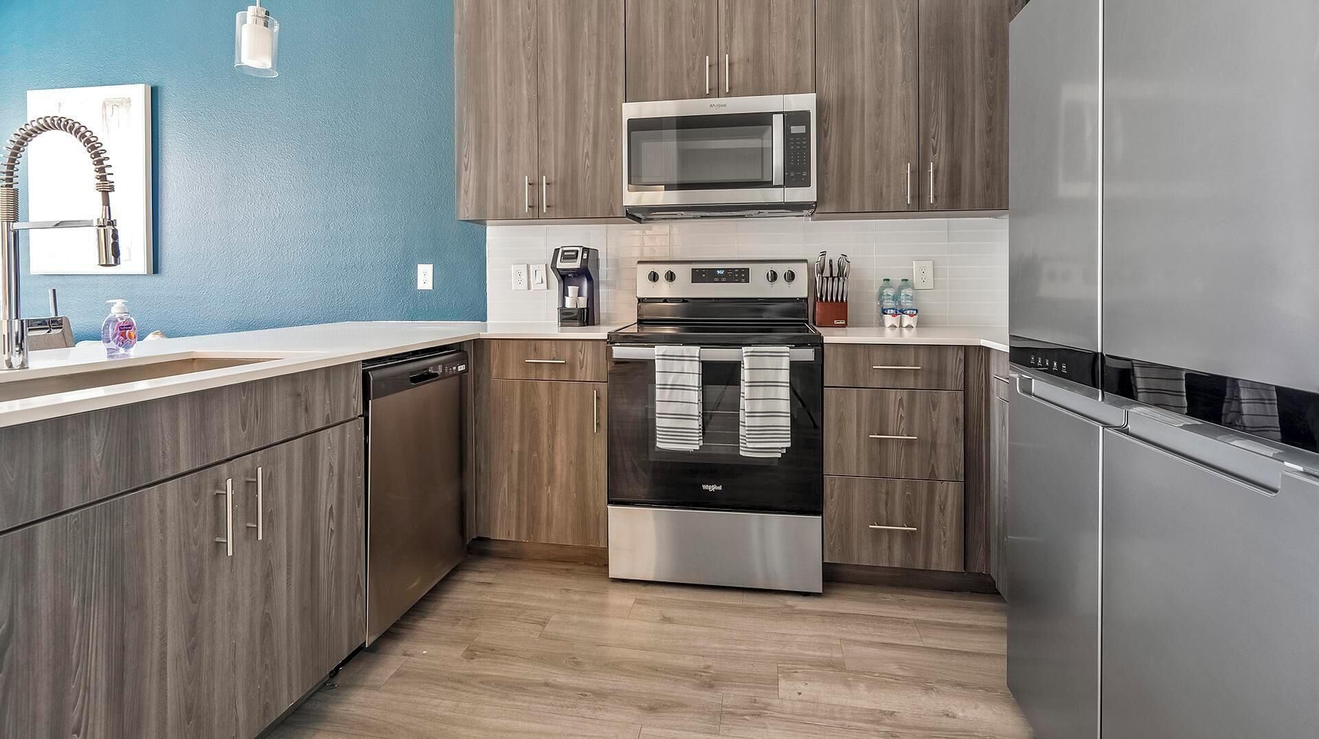 Una cocina moderna con armarios de madera, electrodomésticos de acero inoxidable y una pared de acento azul.