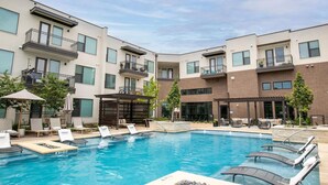 Ein modernes Gebäude mit Swimmingpool, Außenbereich mit Sitzgelegenheiten und einer überdachten Terrasse.
