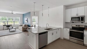 A modern kitchen with white cabinetry, a dishwasher, a stove, and a microwave. - Landing | Beautiful 2BD, Yoga Studio, Pool (Athens)