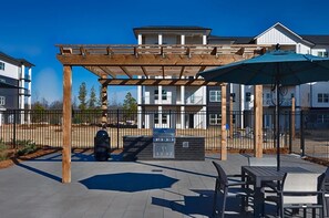 A covered outdoor patio with a pergola, barbecue grill, and outdoor seating area.