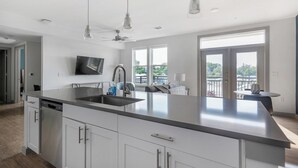 Une cuisine moderne dotée d’un grand îlot central, d’appareils électroménagers en acier inoxydable et d’un téléviseur à écran plat.