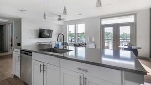A modern kitchen with a large island, stainless steel appliances, and a flat-screen TV. - Landing | Beautiful 1BD, Courtyard, Pool (Austin)