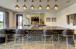 A modern kitchen with a central island, bar stools, and pendant lighting.