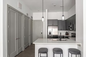 A modern kitchen with a central island, stainless steel appliances, and a bar stool seating area.