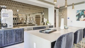 A modern kitchen with a central island, a coffee machine, and a decorative hexagonal wall.