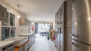 Une cuisine moderne avec un réfrigérateur en acier inoxydable, des armoires grises et un sol carrelé à motifs.