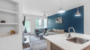 Eine moderne Küche mit weißer Arbeitsplatte, Spüle aus Edelstahl, einer blauen Akzentwand und einem Deckenventilator.