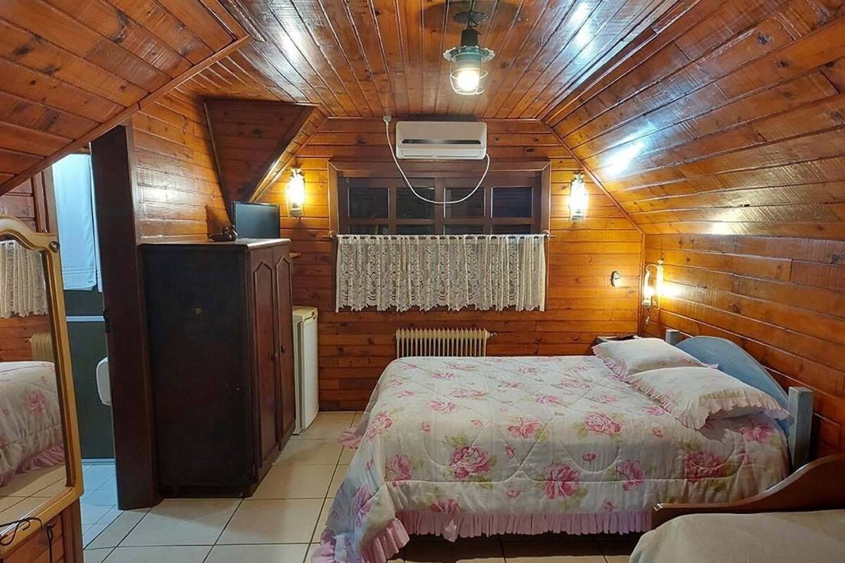 A cozy attic bedroom with wooden walls, a bed with floral bedding, a dresser, and a radiator.