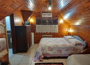 Een gezellig slaapkamer op zolder met houten wanden, een bed met bloemenbeddengoed, een dressoir en een radiator.