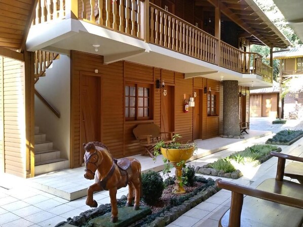 Een houten gebouw met een balkon, een standbeeld van een paard en een bloempot.