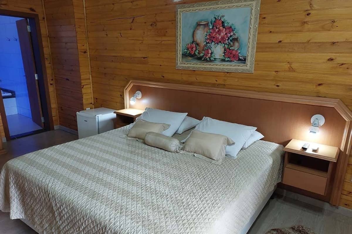 A wooden-paneled bedroom with a bed, bedside tables, and a painting on the wall.