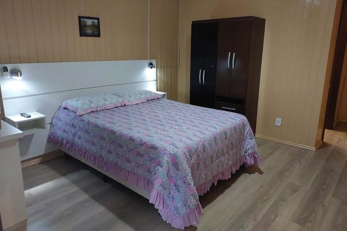 A bedroom with a bed, nightstands, a wardrobe, and a wall-mounted light.