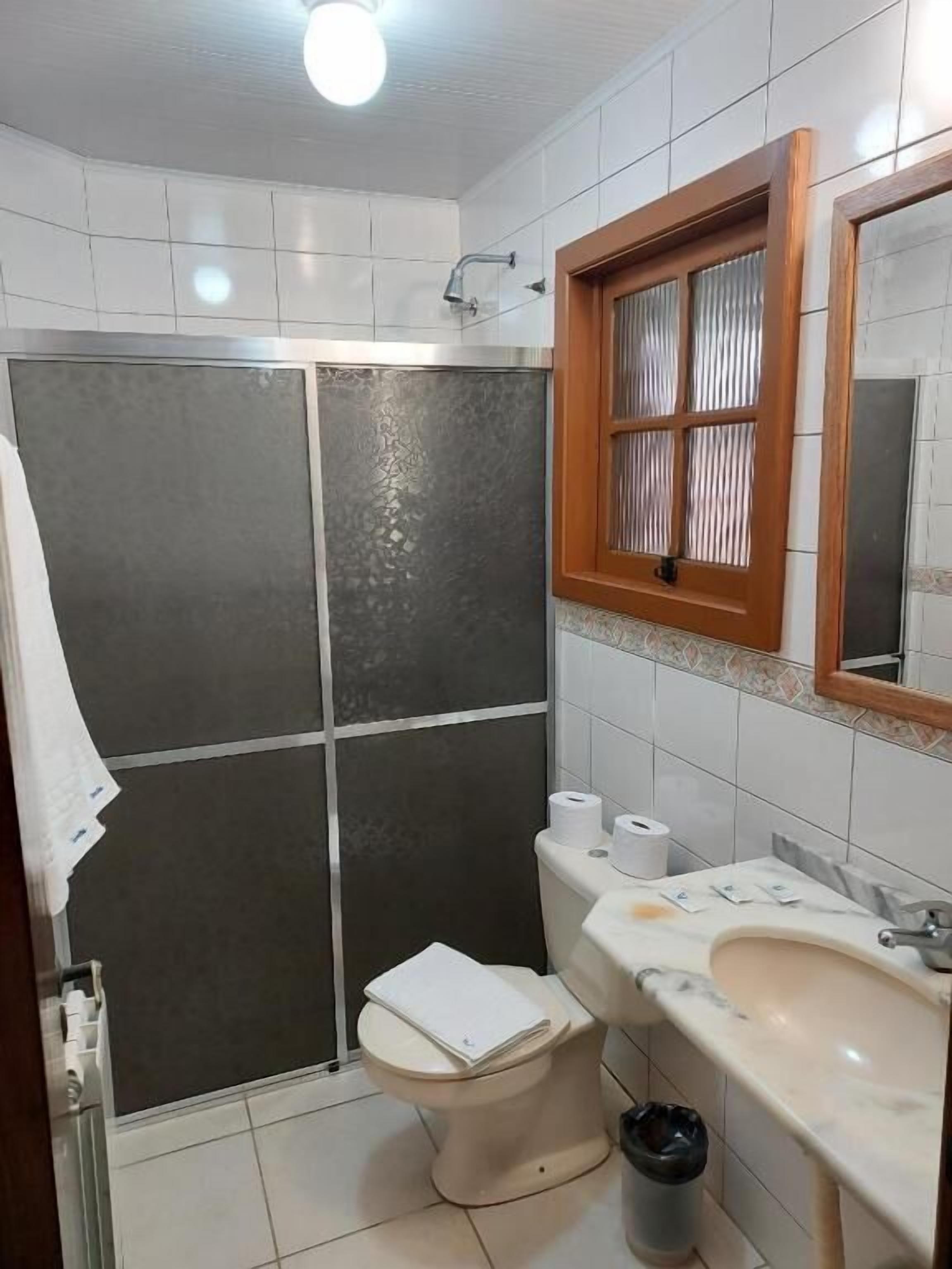 Uma casa de banho com chuveiro, sanita e lavatório.