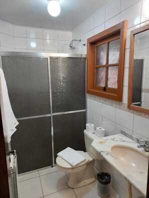 Een badkamer met een douche, toilet en wastafel.