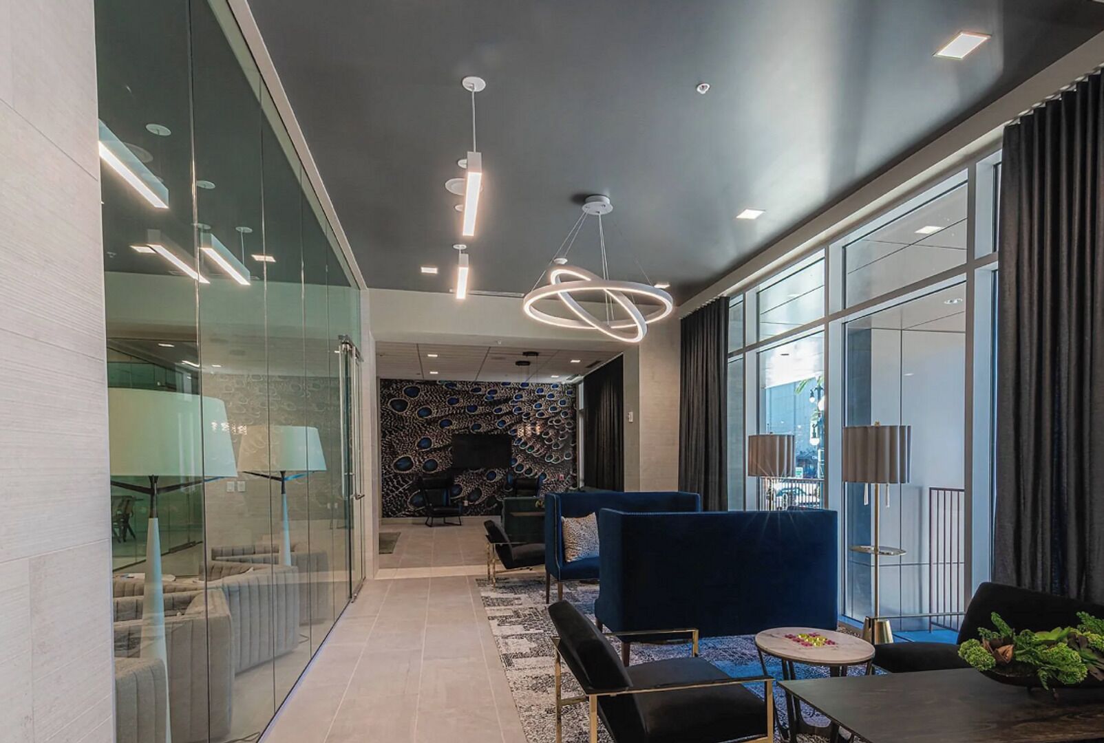 A modern interior with a glass wall, a patterned wall, and a blue sofa.