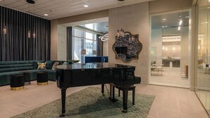 Un salon moderne avec un piano à queue, un canapé vert et un élément décoratif mural.