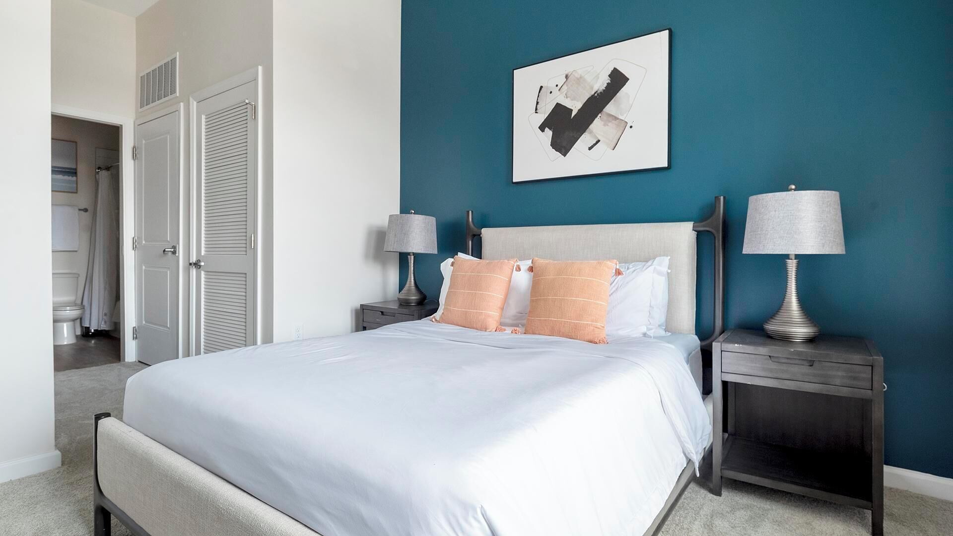 A bedroom with a bed, two nightstands, a headboard, and a wall-mounted artwork.