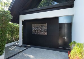 A modern building with a black facade, a large relief sculpture, and a black door.