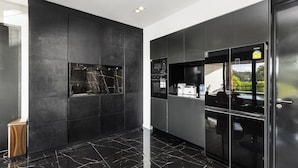 Una cocina moderna con armarios oscuros, horno empotrado y refrigerador con vistas.