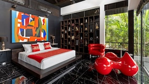 Un dormitorio moderno con una cama grande, una silla roja y una estantería llena de objetos decorativos.