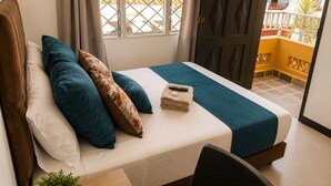 A neatly made bed with pillows, a remote control, and a folded towel on a white mattress. - Hospedajes el Jardin (Envigado)