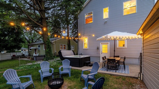 A backyard with outdoor seating, a hot tub, and string lights.