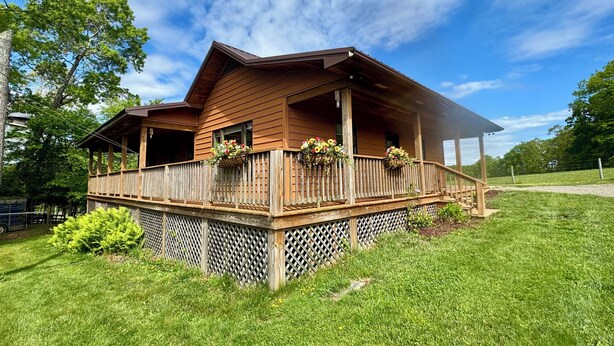 A wooden cabin with a covered porch and flower baskets. - Clara's Cabin (Galax)