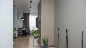 Ein modernes Wohnzimmer mit Essbereich, einem flachbildfernseher an der Wand und zwei Zimmerpflanzen.