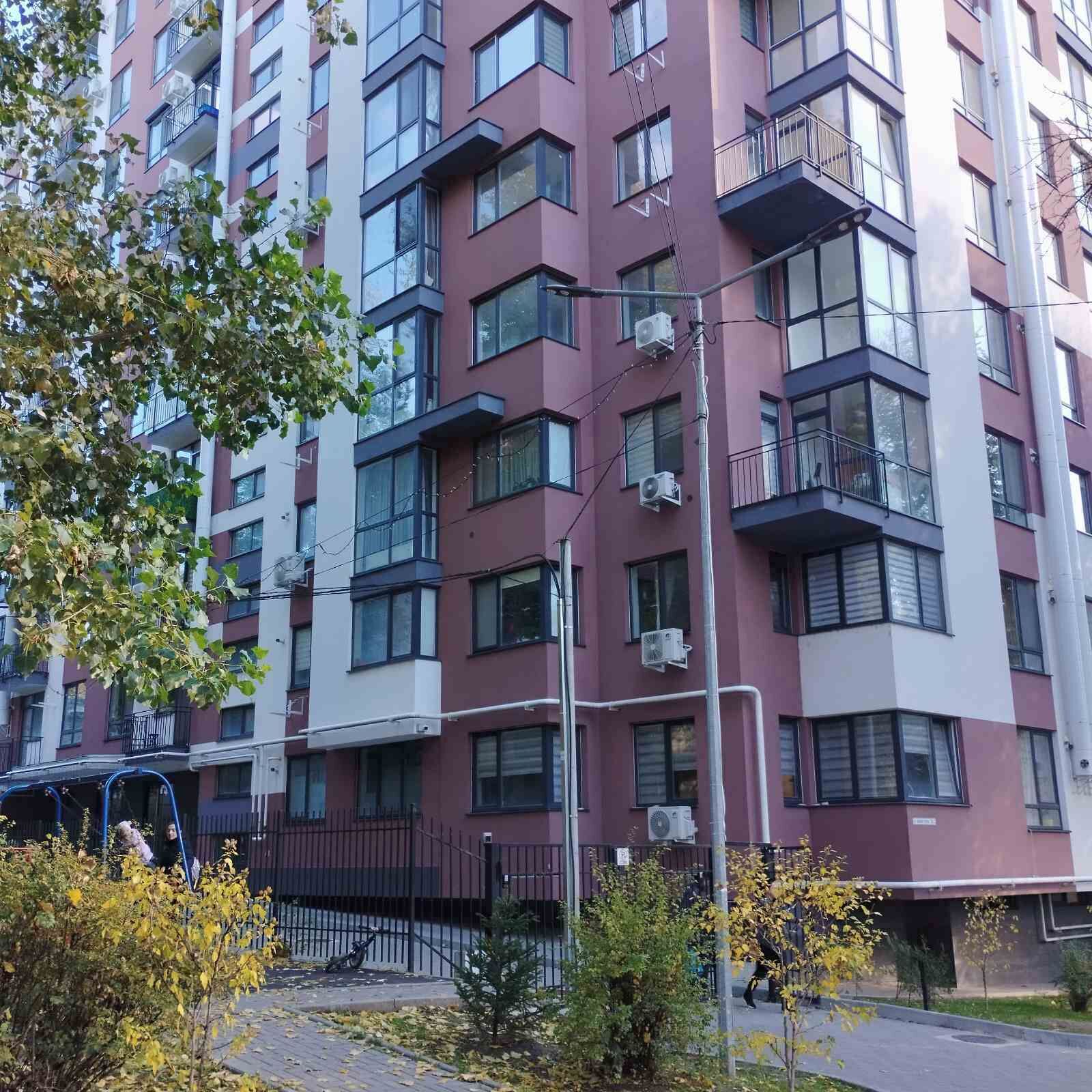 A multi-story residential building with balconies, air conditioning units, and a gated entrance.