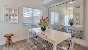 A modern dining area with a white table, clear glass chairs, and a large mirror. - Charming 3-bedroom, 4 Bath Townhome in Arvada, CO (Arvada)