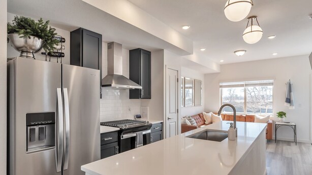 A modern kitchen with a stainless steel refrigerator, a built-in oven, and a large island with a sink. - Charming 3-bedroom, 4 Bath Townhome in Arvada, CO (Arvada)