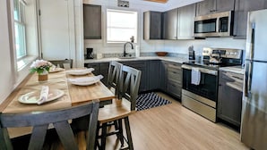 Une cuisine moderne avec un plafond en bois, des appareils électroménagers en acier inoxydable et un coin repas comprenant une table et des chaises.