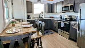 Una cucina moderna con soffitto in legno, elettrodomestici in acciaio inossidabile e un'area pranzo con tavolo e sedie.