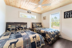 A room with two beds, a ceiling fan, a window, and a wall sign listing animals.