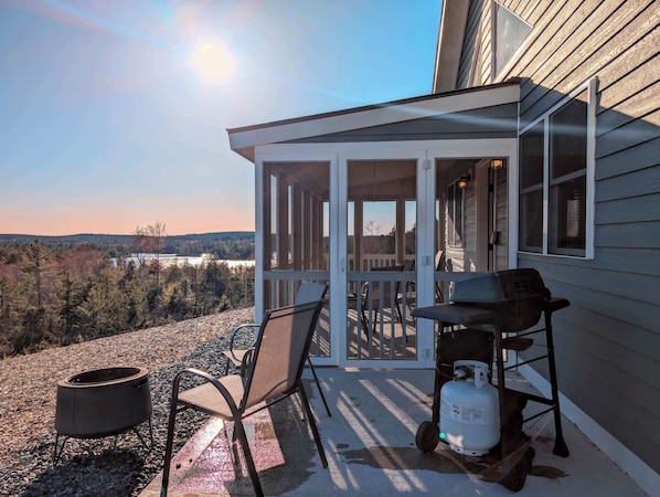A covered outdoor area with a grill, chairs, and a propane tank.