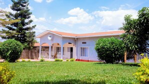 A two-story house with a red roof, white walls, and a covered porch. - Stay in Style! Elegant 4-Bedroom Home in Kigali with Fast WiFi (Kigali)