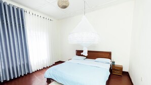 A bedroom with a bed, a nightstand, a lamp, and a window with curtains. - Stay in Style! Elegant 4-Bedroom Home in Kigali with Fast WiFi (Kigali)