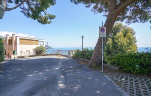 Una strada costiera con un cartello di proprietà privata, un edificio con facciata moderna e vista sul mare.