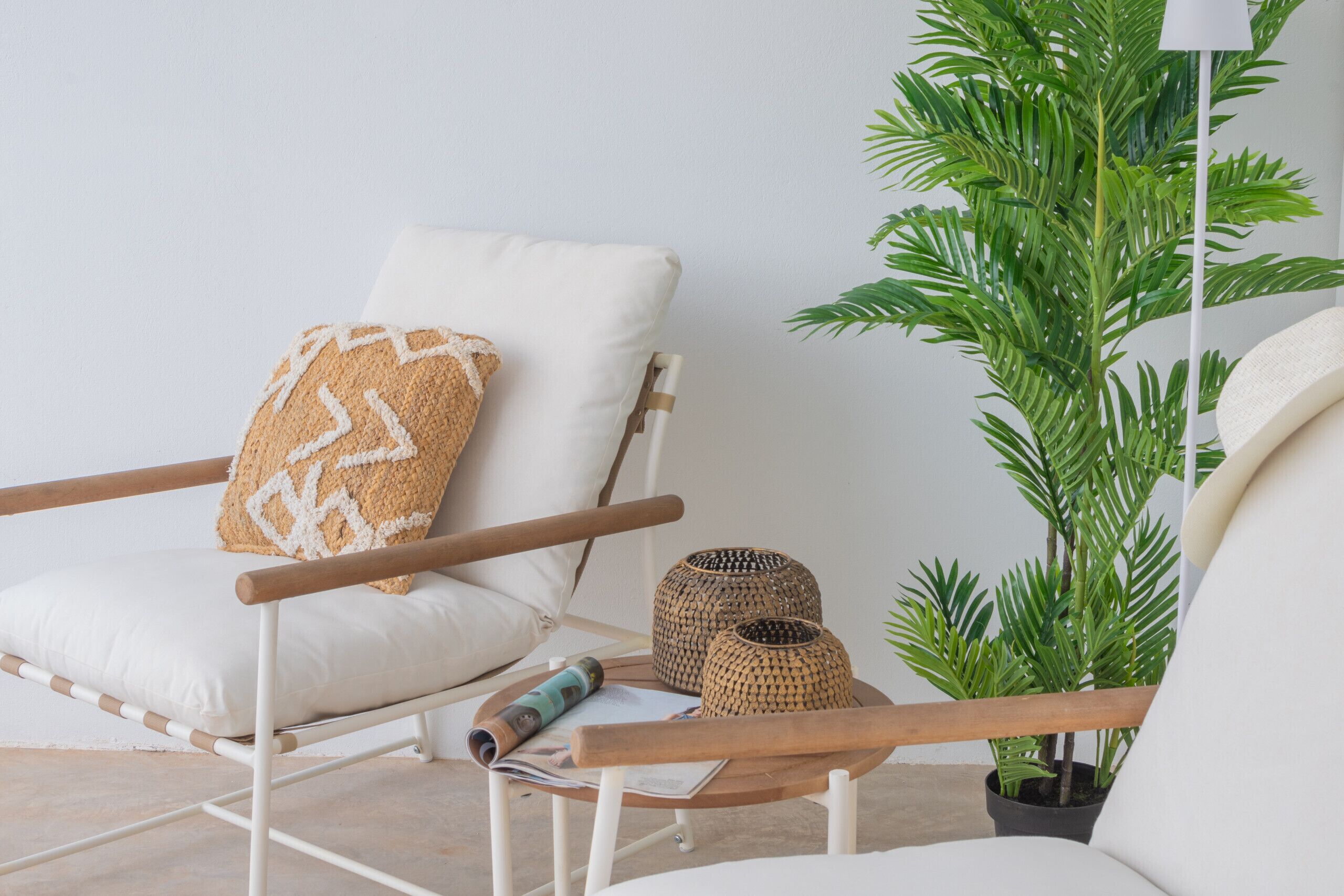 A white chair with a woven pillow, a small woven basket, and a potted plant.
