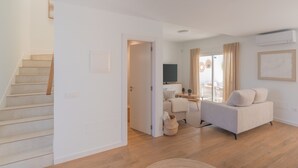 A modern living room with a staircase, a sofa, a TV, and a desk. - Villa Serena Luca (Playa Blanca)