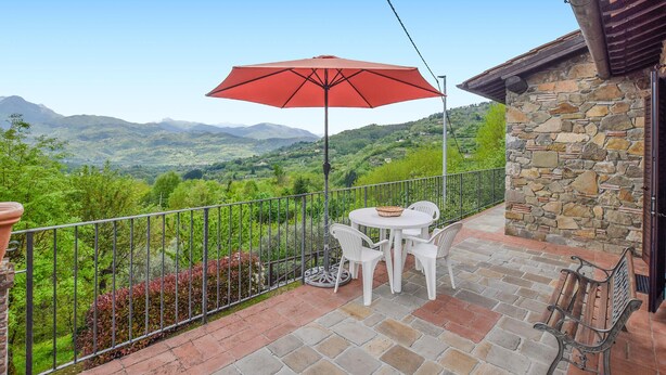 A balcony with a stone wall, a red umbrella, white chairs, and a table. - Awesome home in Barga (Barga)