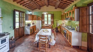 A rustic kitchen with wooden cabinets, a tiled floor, and a dining table with chairs. - Awesome home in Barga (Barga)