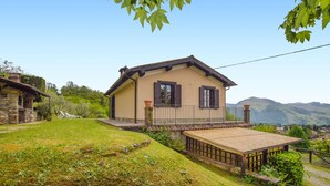 A two-story house with a balcony, surrounded by a grassy yard and a mountain view. - Awesome home in Barga (Barga)