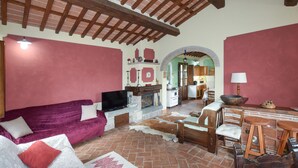 A cozy living room with a fireplace, a television, and a dining area with wooden furniture. - Awesome home in Barga (Barga)