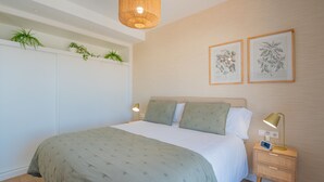 Une chambre à coucher avec un lit, des lampes de chevet, une table de chevet et des plantes fixées au mur.